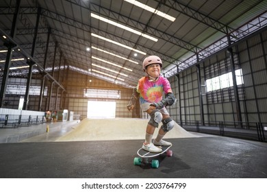 asian child skater or kid girl enjoy fun playing skateboard or smile ride surf skate on wave ramp at indoor skate park by extreme sports to wearing helmet wrist knee support for body safety on summer - Powered by Shutterstock