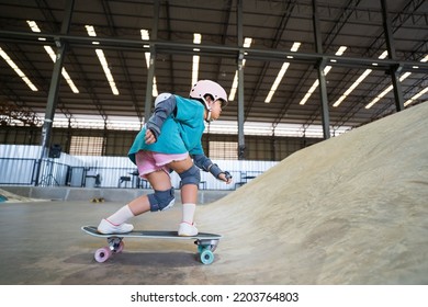 asian child skater or kid girl playing skateboard or ride surf skate up to wave ramp or wave bank to fun bottom turn in skate park by extreme sports surfing to wear helmet knee support for body safety - Powered by Shutterstock