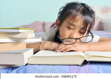 Asian Child Sleeping While Reading In The Bed. Girl With Glasses Studying Asleep, Selective Focus And Vintage Style