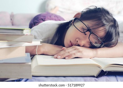 Asian Child Sleeping While Reading In The Bed. Girl With Glasses Studying Asleep In Split Tone , Selective Focus And Vintage Style