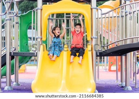 Asian child smiling playing on slider bar toy outdoor playground, happy preschool little kid having funny while playing on the playground equipment in the daytime in summer, Little girl boy climbing
