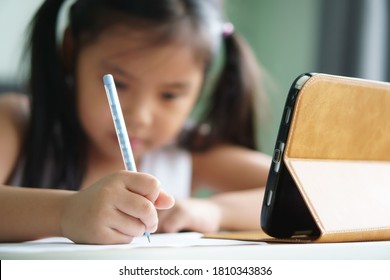 asian child student back to school or kid girl smile write note or draw by pencil and read on computer tablet with doing homework to new idea think or people learn from home study online on smartphone