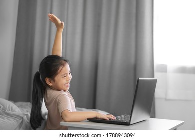 Asian Child Student Or Kid Girl Smile Enjoy And Hand Up Or Raise One's Hand On Computer Notebook For Communication And Study Online Or Learn From Home To Play Laptop For Education School By Stay Safe