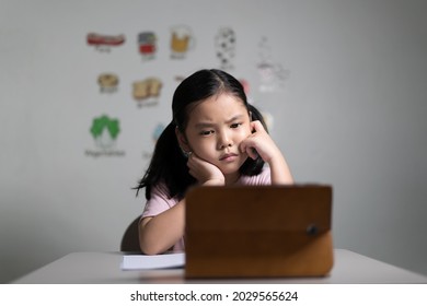 Asian Child Student Or Kid Girl Stressed Thinking And Unhappy Learning On Computer Tablet Video Call Or Frown Bored To Study Online By Smartphone Or People Learn From Home School By English Vocabulary