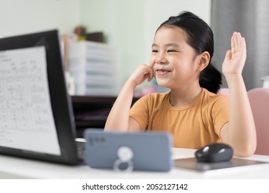 Asian Child Student Or Kid Girl Smile Enjoy And Hand Up Or Raise One's Hand On Computer Laptop And Smartphone For Video Call To Study Online Or Learn From Home And Play Notebook For Education School