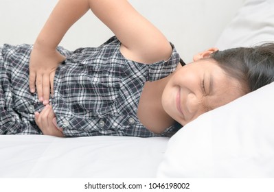 Asian Child Suffering From Stomachache And Lying On Bed. Diarrhea Or Healthy Concept