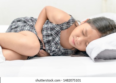 Asian Child Suffering From Stomachache And Lying On Bed. Diarrhea Or Healthy Concept