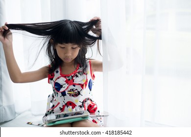Asian Child with tablet sitting near window