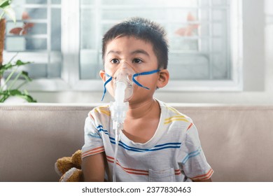 Asian Child using nebulizer mask equipment alone have smoke, Kid boy making makes inhalation nebulizer steam sick cough at home, oxygen spray inhaler therapy, stuffy nose and runny, Health medical - Powered by Shutterstock