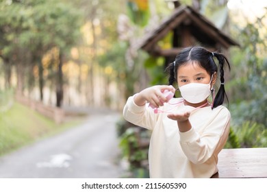 Asian Child Wearing Face Mask Or Kid Girl Holding And Press Alcohol Gel On Hand For Sterilizing Or Kill Disease Covid-19 Coronavirus And Clean Hands Or Person Use Alcohol Liquid On Outdoor Travel