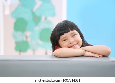 Asian Children Cute Or Kid Girl Happy Fun And Smile With Wear Red Shirt On Sofa At Preschool Or Nursery And Child Hospital With Space