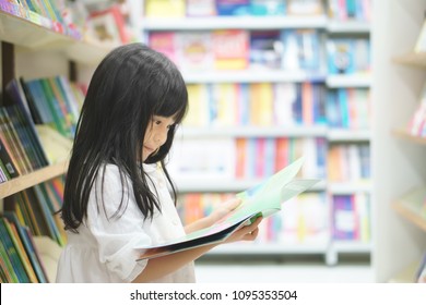 Asian Children Cute Or Kid Girl Smile Reading And Choose Tale Or Story Book On Bookshelf In Bookstore Or Library Room At School Or Nursery For Learning And Studying With Education