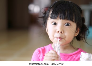 Asian Children Cute Or Kid Girl Drinking Water Or Soy Milk Beverage In Bottle By Tube Or Straw And Eating Snack Or Dessert