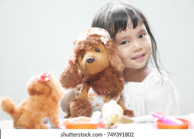 Asian children cute or kid girl smile with fun and enjoy playing dog doll for relax and learning at nursery home on soft focus