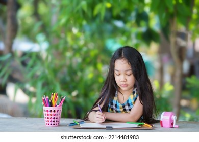 Asian Children Drawing With Pencil. Close Up Portrait Child Drawing With Colored Paints On Paper. Cute Little Child Girl Is Sitting And Painting.