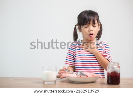 Asian children girls eating bread and desserts and sticking in one's throats with choked food or puke  on the table at home for breakfast or lunch