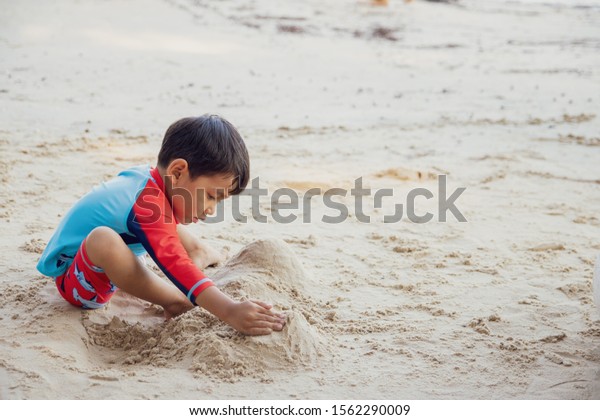 Asian\
children play in the sand on the beach in\
summer.