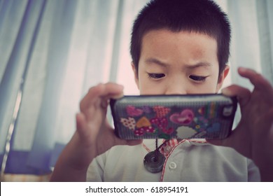Asian children play smartphone on bed