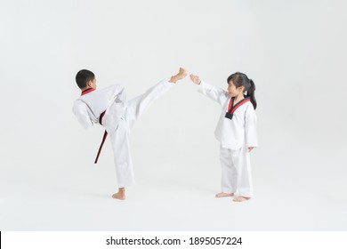 Asian Children Practicing Taekwondo In White Studio 