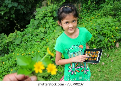 Asian Children Searching For Flower Species By Tablet In The Garden, Learning Biology Plant Outside The Classroom.