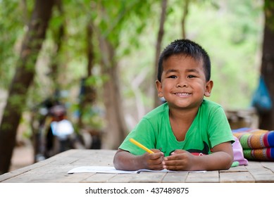 Asian Children Study At Old Home. Poor Kid Learning To Drawing, Painting With Color Pencil. Poverty Child, Smile, Lying On Dirty Wooden Table And Writing On Book. Poor Quality Education Concept