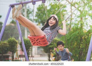 Asian Children Swinging On The Playground