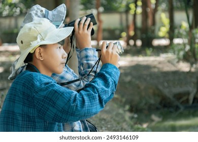 Asian children using binoculars to do the birdwatching in tropical forest during summer camp, idea for learning creatures, wildlife animals and insects outside the classroom. - Powered by Shutterstock