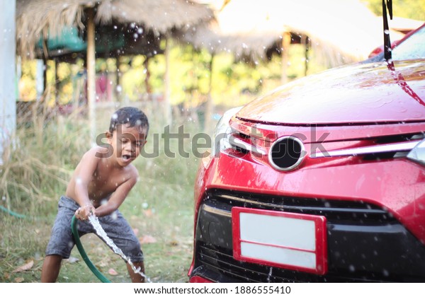 Asian children washing car in the garden.\
Freedom and relax time in summer\
holiday.