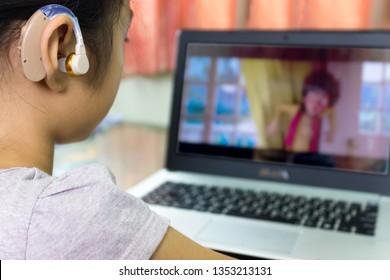 Asian children watch cartoons using hearing aids.