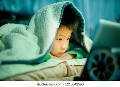 asian chinese boy playing smartphone on bed, watching smartphone, kid use phone and play game, child use mobile, addicted game and cartoon, boy play phone
