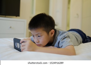 Asian Chinese Boy Playing Smartphone On Bed, Kid Use Phone And Play Game, Addicted Game And Cartoon, 
