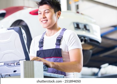 Asian Chinese Car Mechanic Checking Auto Engine With Diagnostics Tool In His Workshop