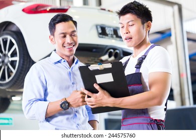 Asian Chinese Car Mechanic With Customer Going Through The Maintenance Checklist