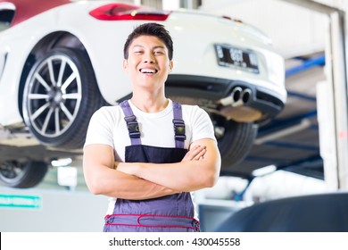 Asian Chinese Car Mechanic Standing In Front Of Luxury Car In Auto Workshop