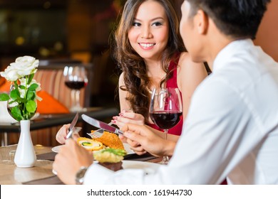 Asian Chinese couple - Man and woman - or lovers flirting and having a date or romantic dinner in a fancy restaurant 