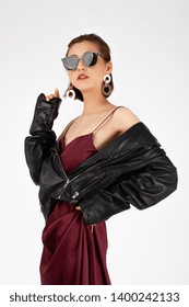 Asian Chinese Fashion Influencer Modeling In A Wine Color Silk Dress And Leather Jacket Isolated In White Background