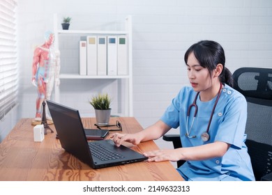 Asian Chinese Female Doctor Using Computer Laptop In Office,  Professional Specialist Medical Healthcare Staff In Hospital, Wearing White Coat Stethoscope Working During Covid19 Pandemic. 