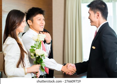 Asian Chinese Hotel Manager Or Director Or Supervisor Welcome Arriving VIP Guests With Roses On Arrival In Luxury Or Grand Hotel