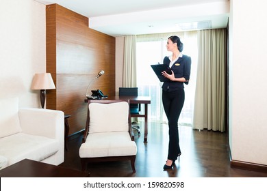 Asian Chinese Housekeeping Manager Or Assistant Controlling Or Checking The Room Or Suit Of A Hotel With A Checklist On Tidiness 