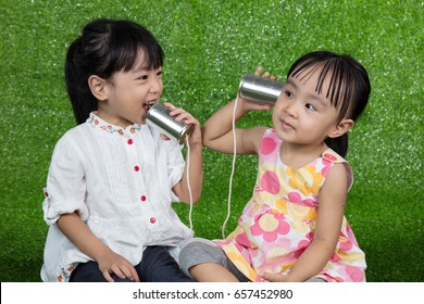 Asian Chinese Kids Playing With Tin Can Phone On Green Grass