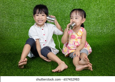 Asian Chinese Kids Playing With Tin Can Phone On Green Grass