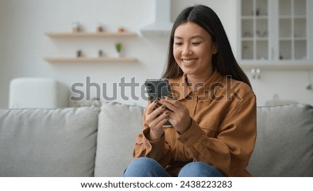 Asian chinese korean businesswoman woman girl freelancer work from home in kitchen read good news smiling use mobile phone choose goods on internet order delivery online typing message cellphone chat