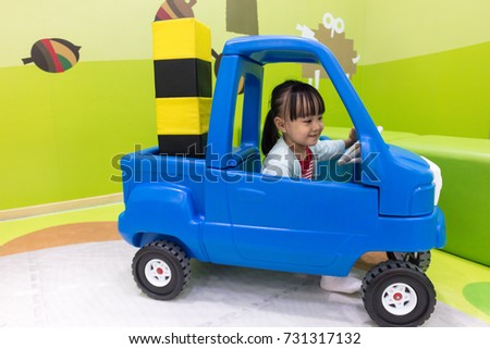 Asian Chinese little girl driving toy car at indoor playground