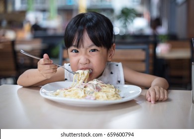 Asian Chinese Little Girl Eating Spaghetti At Outdoor Cafe