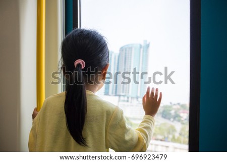 Asian Chinese little girl inside a MRT transit looking far way beside the window