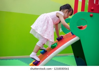 Asian Chinese Little Girl Playing At Mini Rock Climbing Wall At Indoor Playground