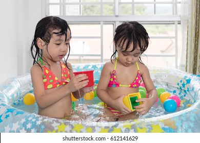 Asian Chinese Little Sisters Playing In The Inflatable Pool Inside The House.