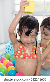 Asian Chinese Little Sisters Playing In The Inflatable Pool Inside The House.