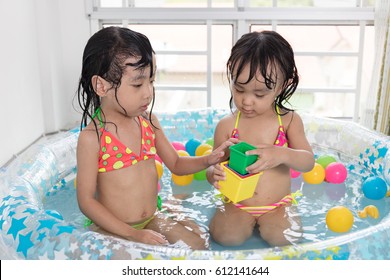 Asian Chinese Little Sisters Playing In The Inflatable Pool Inside The House.