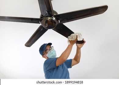 An Asian Chinese Male Cleaning Ceiling Fan At Home. 